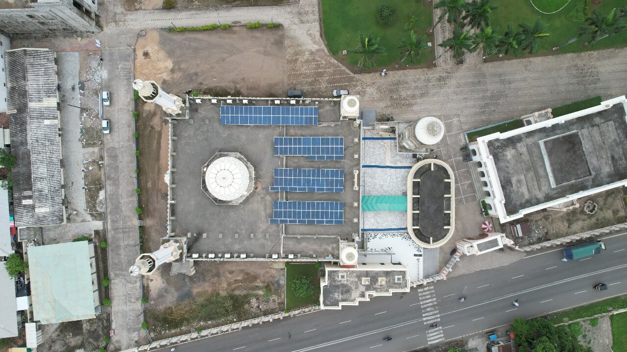 Overhead view of solar arrays next to minarets on a Madrasa Jamia Islamia rooftop overlooking a roadway