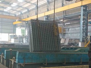 Metal grating panels suspended above a galvanizing tank in the workshop
