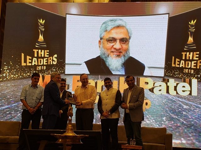 Award ceremony photo showing Faruk Patel receiving “The Leaders 2019” award on stage