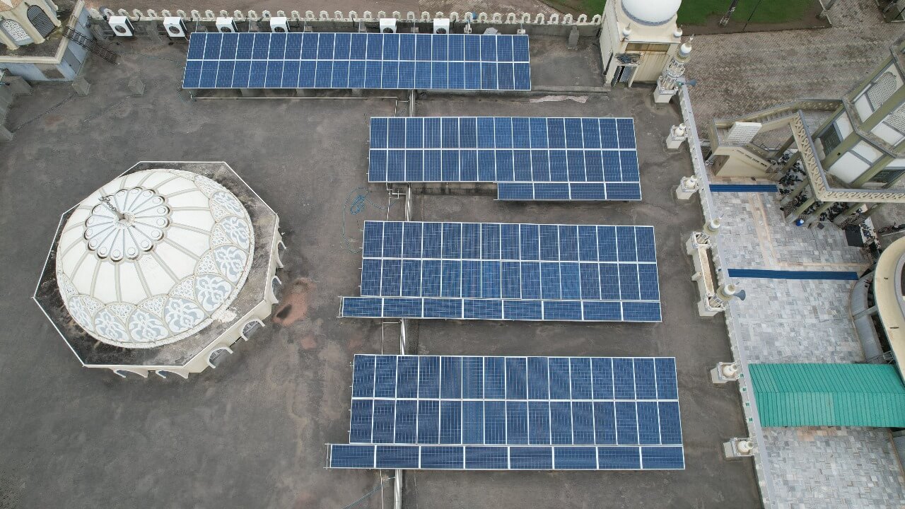 Aerial view of solar panel rows at Madrasa Jamia Islamia on a flat rooftop