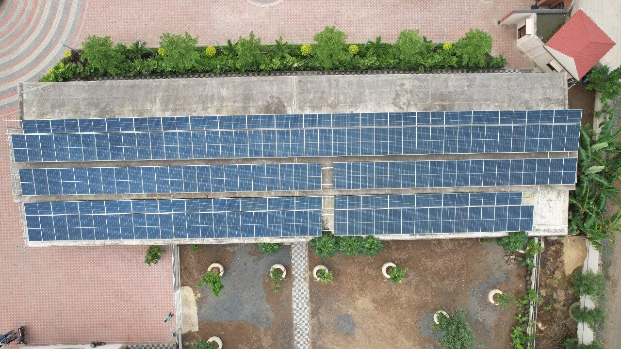 Top-down view of solar PV arrays on a concrete carport roof with landscaped garden below at Green Lab Farm House