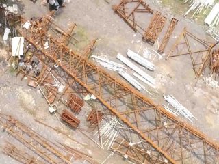 Top-down view of rust-colored lattice tower sections and spare steel members