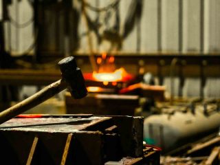 Hammer resting beside a glowing hot metal workpiece on an anvil
