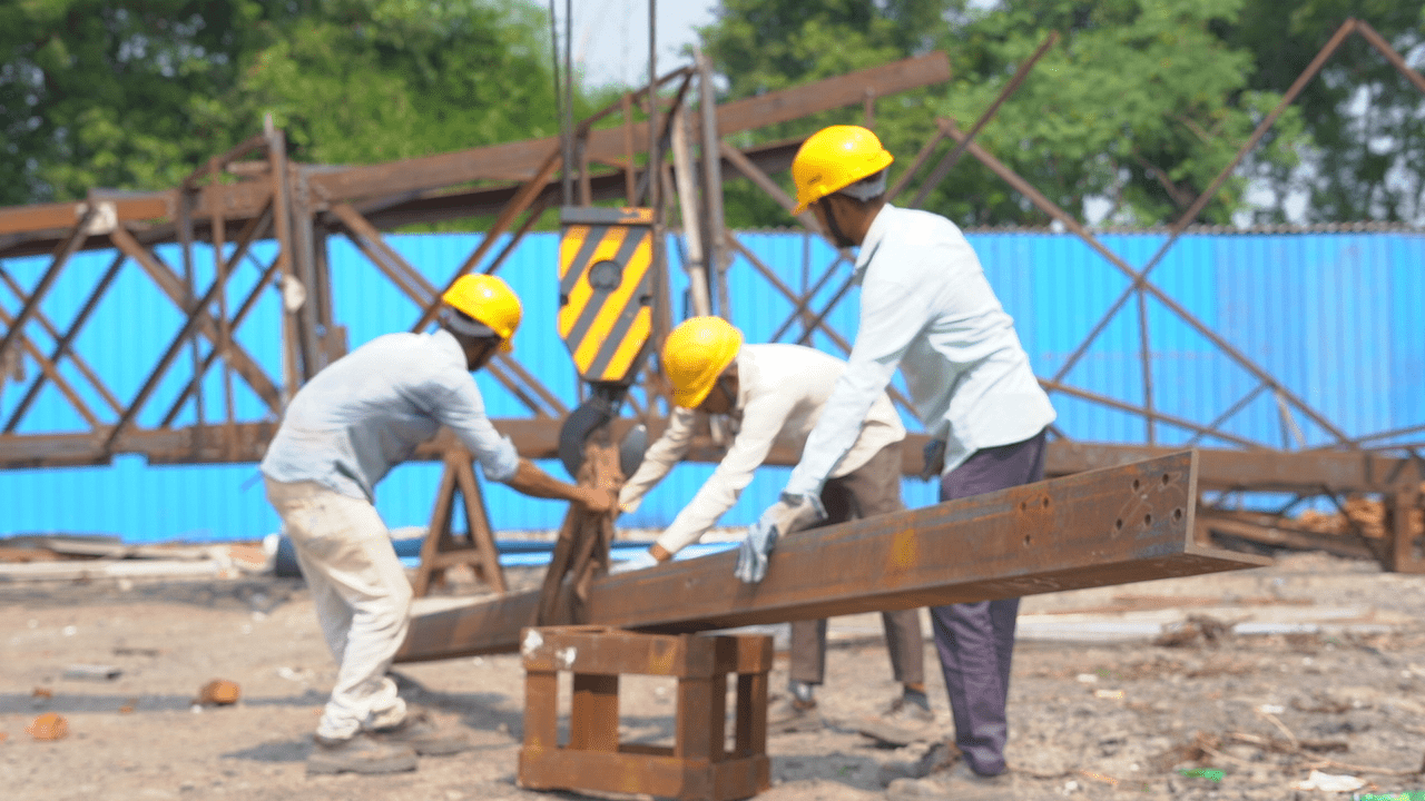 Workers assembling the steel framework of a pre-engineered building at a construction site.