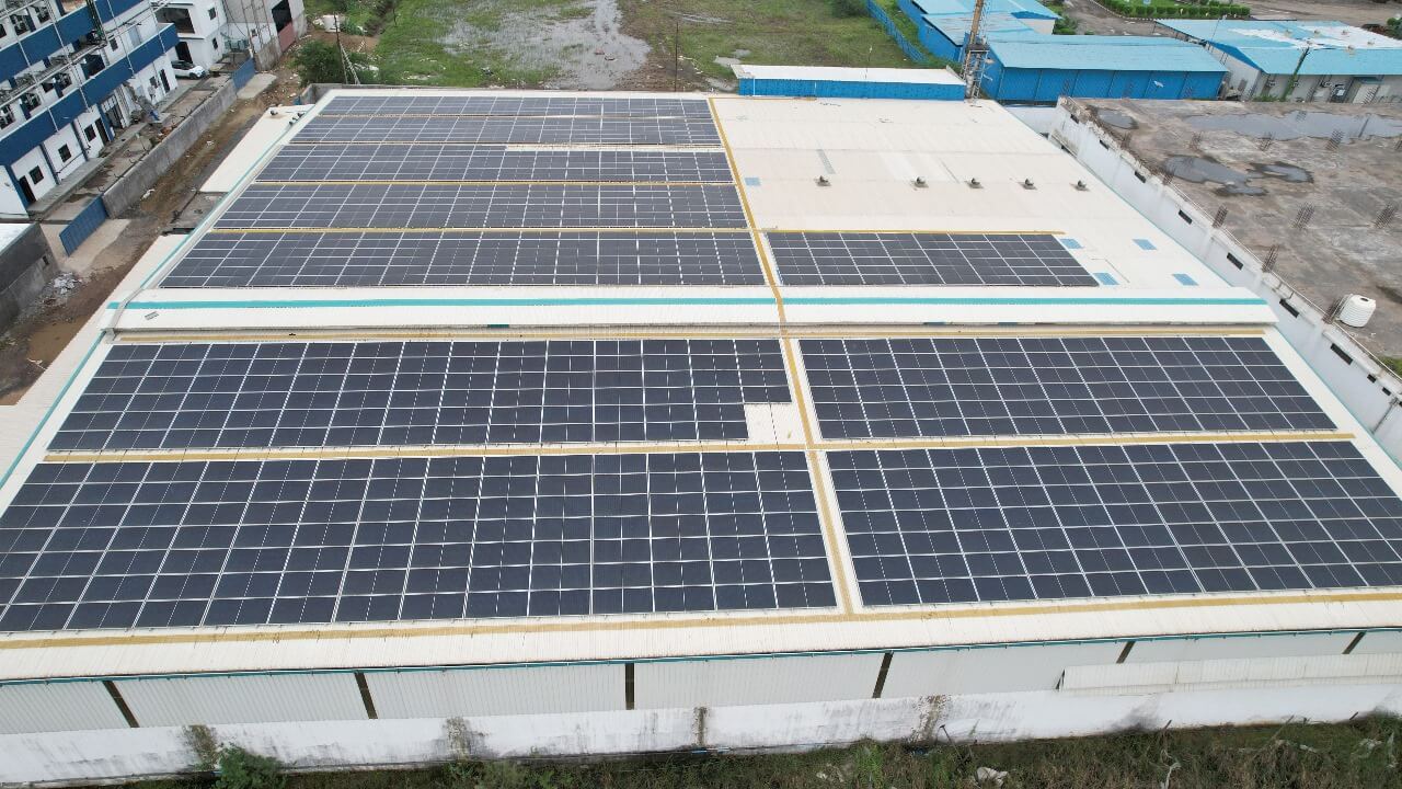 Angled aerial image of solar panel clusters on a corrugated roof of an Nipun  industrial plant
