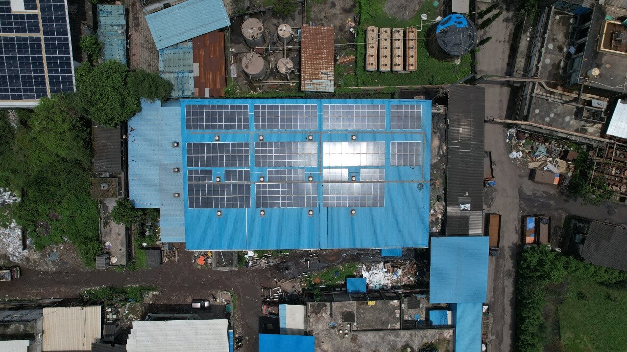 Top‐down shot of solar modules on a Zab Sizer factory blue roof with adjacent equipment yards